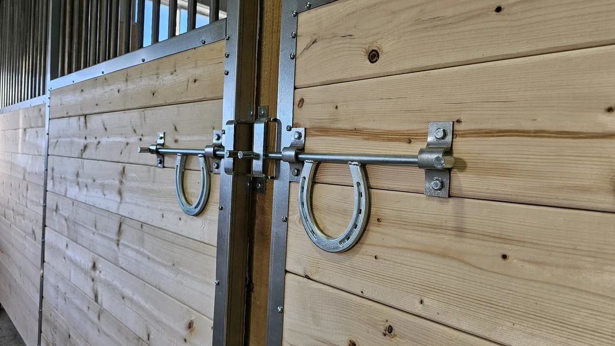 Détail de poignée et loquet sur une façade de box pour chevaux