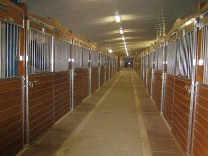 Longue allée d’écurie avec alignement de box pour chevaux Equinad.