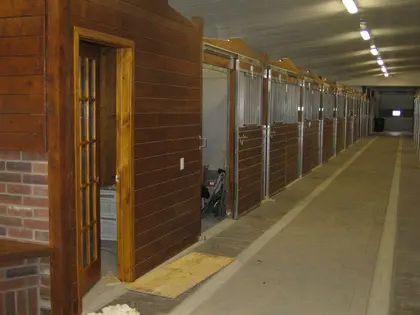Allée d’écurie avec box pour chevaux en bois et métal sur mesure.