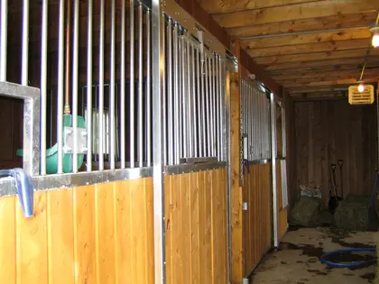 Façade de box en bois et métal installée dans une écurie.