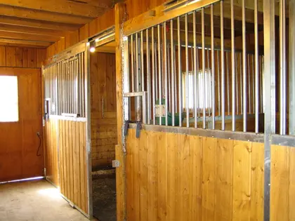 Box pour chevaux en bois avec barreaux métalliques et fabrication sur mesure.