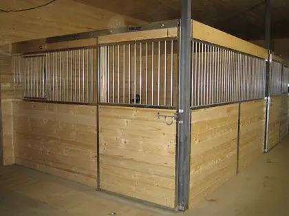 Façade de box pour chevaux en bois clair avec cadre métallique galvanisé.