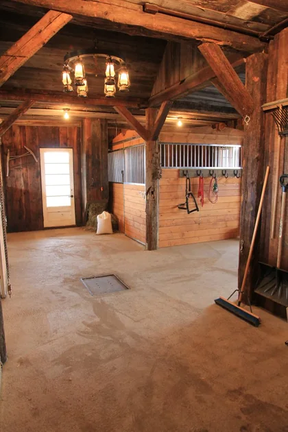 Écurie rustique avec box pour chevaux Equinad, boiserie, barreaux galvanisés et ambiance chaleureuse.